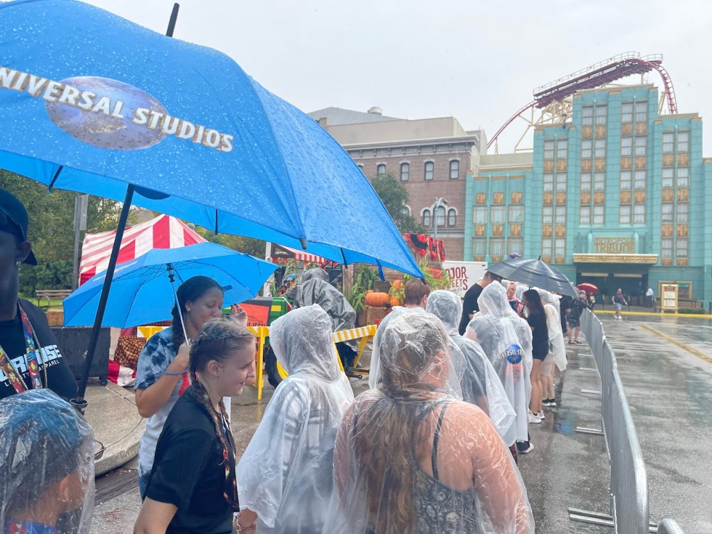A group of people standing in the rain at Universal Orlando with umbrellas.
