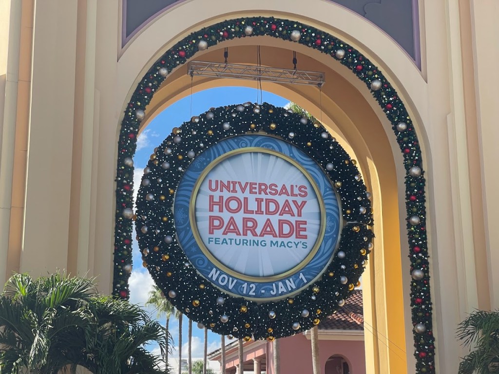Holidays at Universal Orlando large wreath in Universal Studios Florida entrance archway reading "Universal's Holiday Parade Featuring Macy's Nov 12- Jan 1"