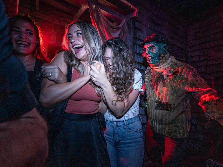 Halloween Horror Nights 2026 Tickets & Passes Guide 4 Friends reacting inside a Halloween Horror Nights haunted house