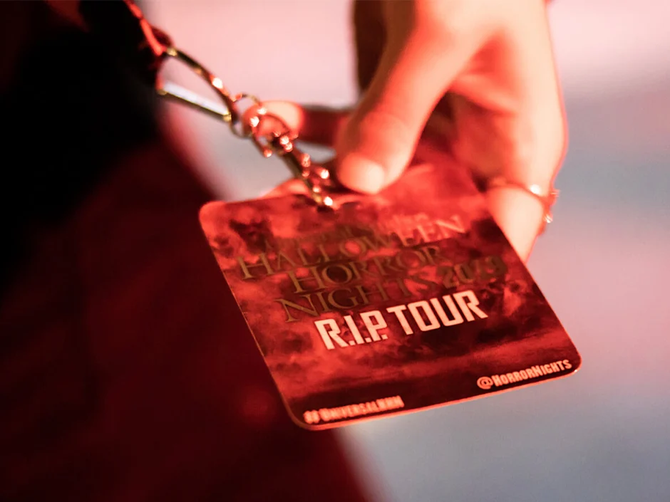 Halloween Horror Nights 2026 Tickets & Passes Guide 5 Guest holding an RIP Tour badge at Halloween Horror Nights