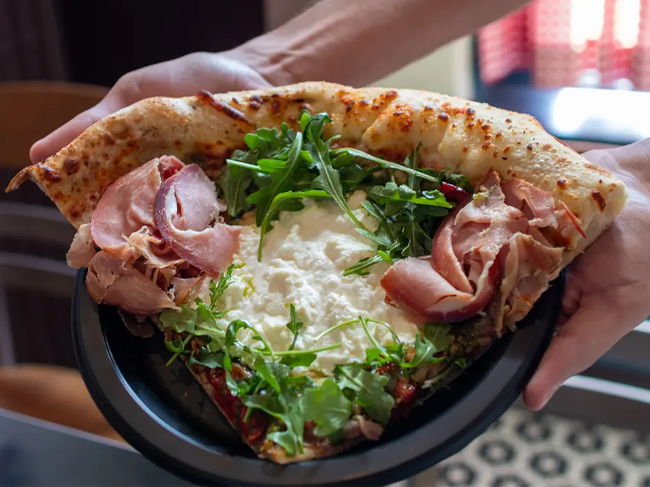 Universal Orlando Passholder Appreciation Days 2026 Menu Revealed 5 Prosciutto and arugula pizza slice at Louies Italian Restaurant