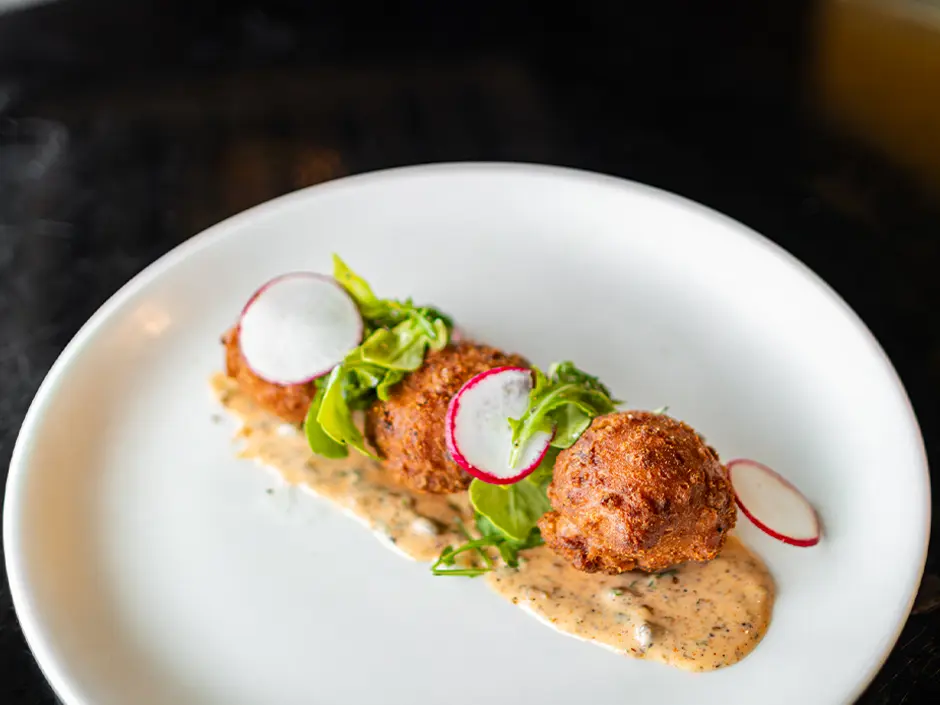 CityWalk Adds a Mac and Cheeseburger for Football Season 4 Corn fritters with radish slices and greens over a creamy sauce