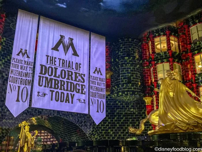 Epic Universe Crowds Ease, but Two Rides Still Need a Plan 1 Dolores Umbridge trial banners beside a golden statue inside the Ministry of Magic