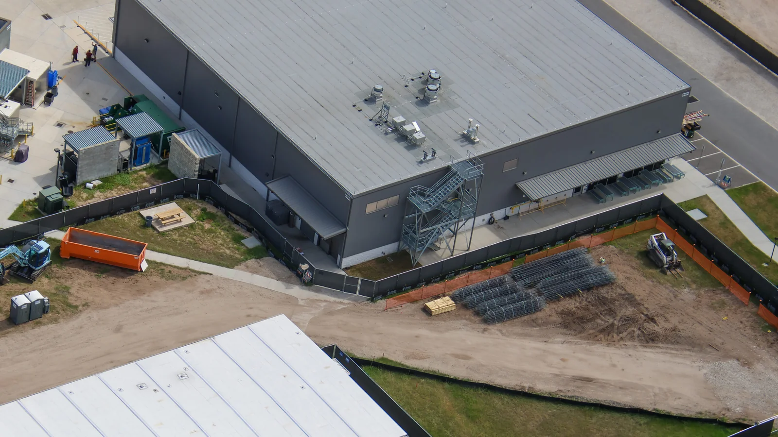 Foundation Work Advances Behind Dark Universe at Epic Universe 2 Stacks of reinforcement material beside a backstage building near Dark Universe