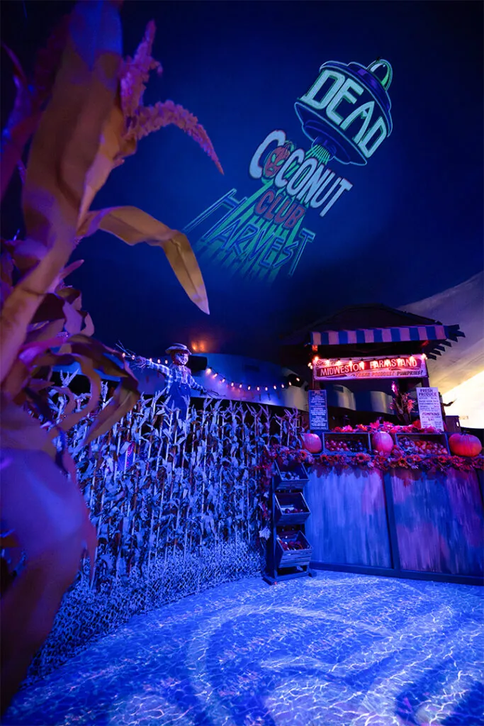 Dead Coconut Club’s Alien Invasion Brings Its First Food Menu to CityWalk 2 Corn stalks and a bar beneath the Dead Coconut Club sign
