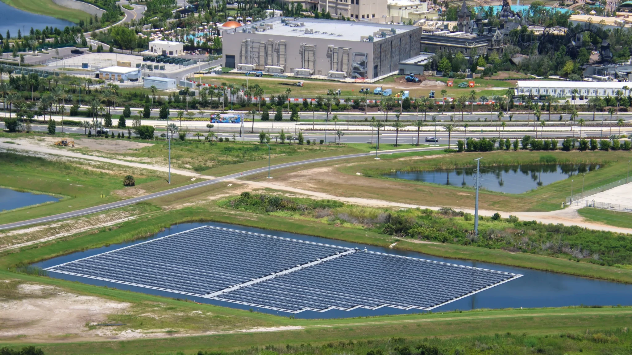 Epic Universe Uses Floating Solar Panels to Charge Electric Buses 2 Floating solar panels in a retention pond with Epic Universe and Dark Universe across the road